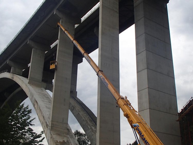 Foto: Grünhüblbrücke: Ansicht des Brückenbogens aus der Froschperspektive; ein Teleskopkran ist mit der Abtragung von Teilen beschäftigt