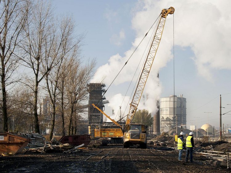 Foto: Kokerei Linz: Blick auf die Sanierungsfläche; im Vordergrund zwei Arbeiter, im Hintergrund ein großer Baggerkran 